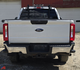 Ford F-350 Super Duty rear view with plow setup and towing hitch, crew cab, white exterior, chrome bumper, taillights visible.
