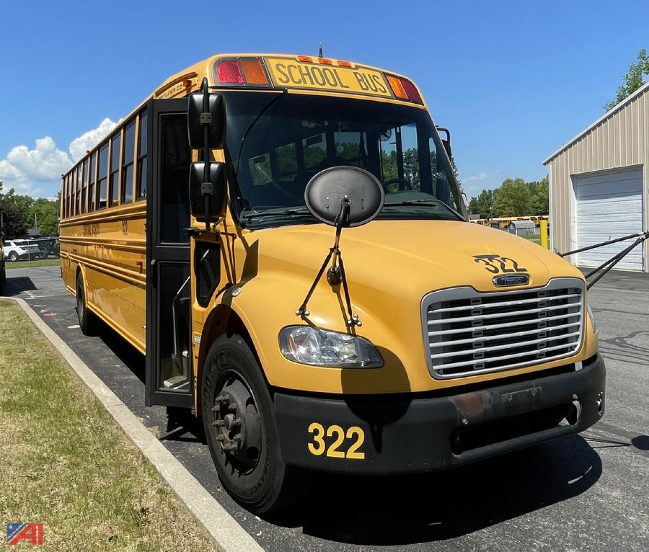 Front-left view of a yellow 2014 Freightliner C2 school bus with 'SCHOOL BUS' sign, black bumper, large circular side mirror, and number 322 on the front fender.
