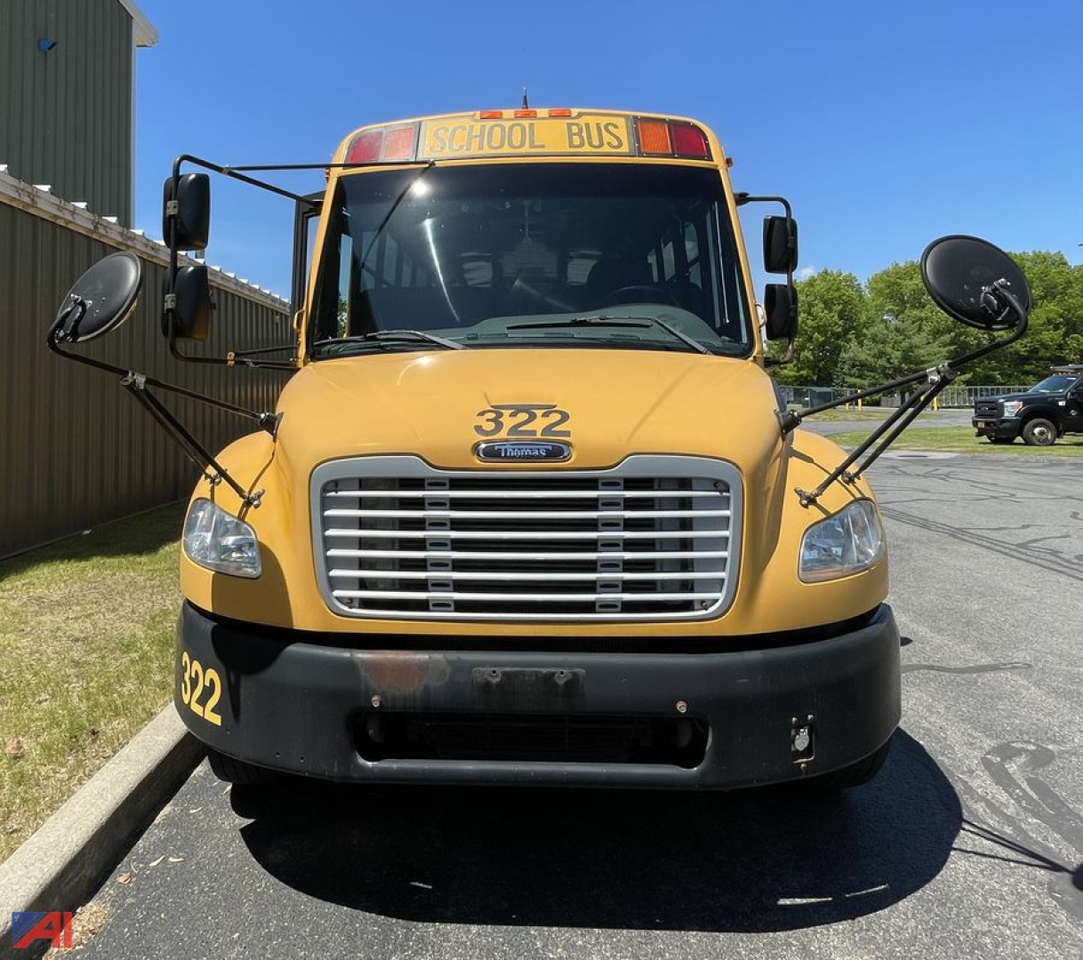 Front view of a yellow 2014 Freightliner C2 school bus showing front grille, black bumper, windshield, headlights, and school bus sign above the windshield.