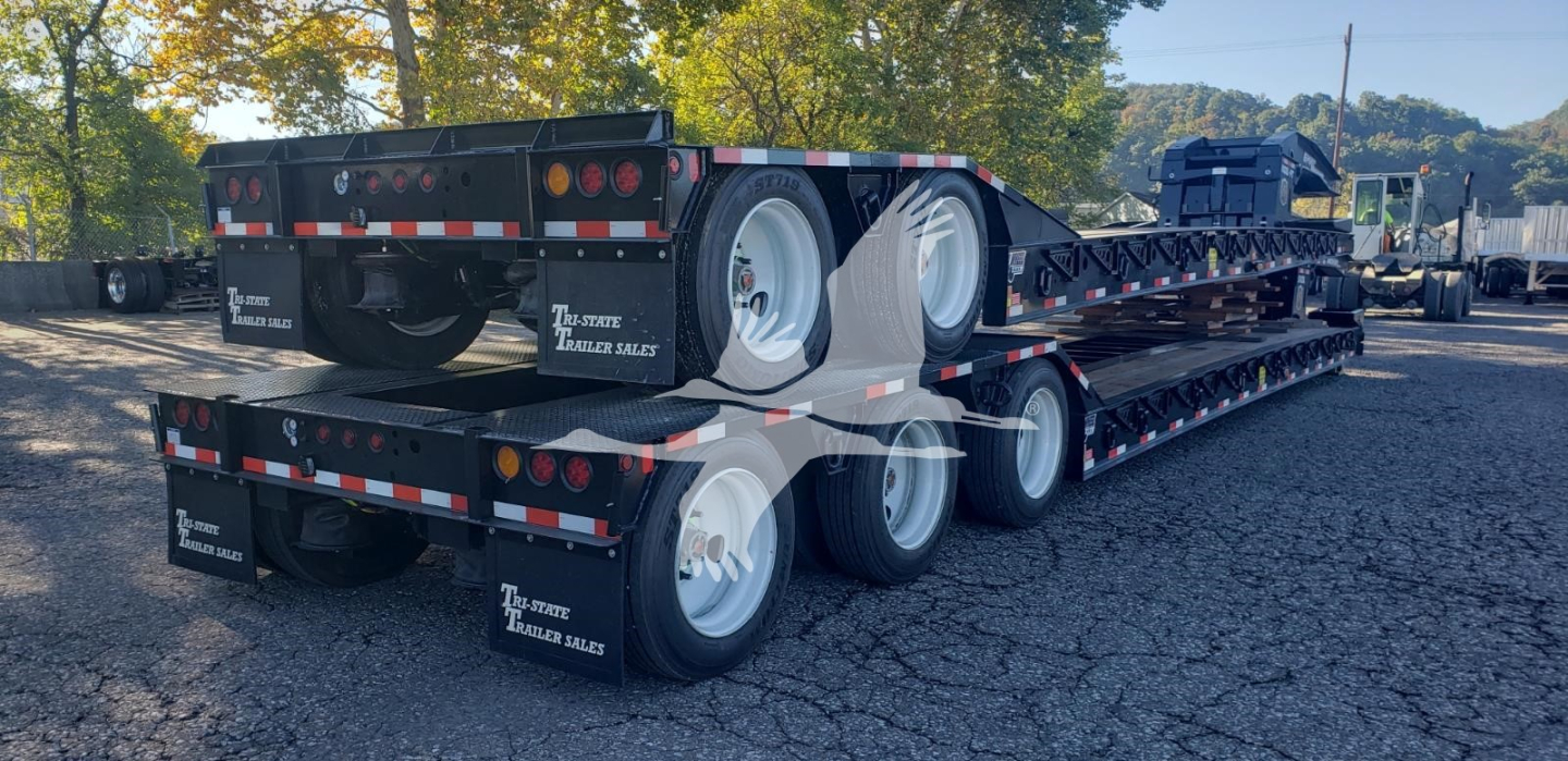 Trailer with multiple axles showing lowboy deck and dual rear tandems; visible text on mudflaps reads 'The Trailer Digest' or similar; no legible model text clearly visible.