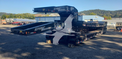 Trailer deck stacked with Eager Beaver 50Gsl-3 high-density lowboy trailer showing logos and crane arm, side view with black color and white eagle graphic.