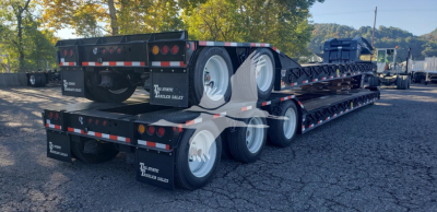 Trailer with multiple axles showing lowboy deck and dual rear tandems; visible text on mudflaps reads 'The Trailer Digest' or similar; no legible model text clearly visible.