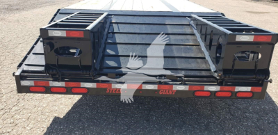 Drop deck trailer showing rear view with steel deck, taillights, and spare recesses; stickers include brand markings and reflective elements.