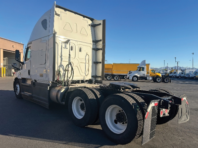 Truck chassis rear view of a 2023 Freightliner Cascadia126 with sleeper cab, showing rear wheel axles and mud flaps.