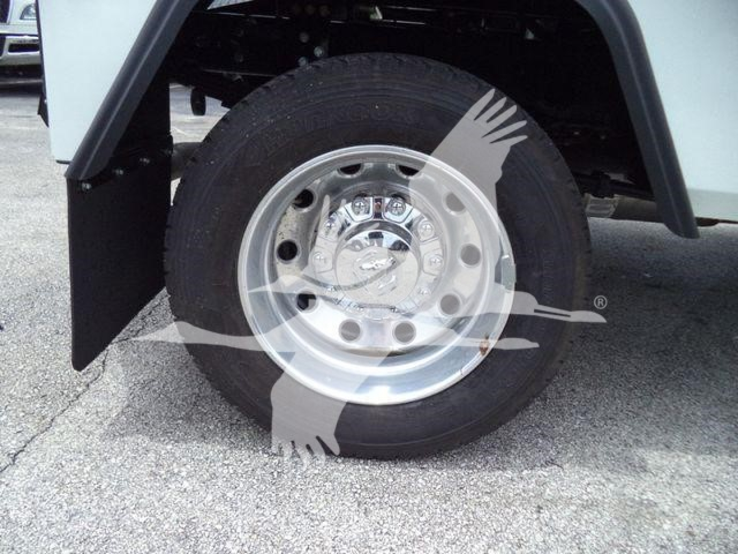 Truck wheel close-up showing aluminum wheel with hubcap and tire, fender flare and part of wheel well; watermark overlay present.