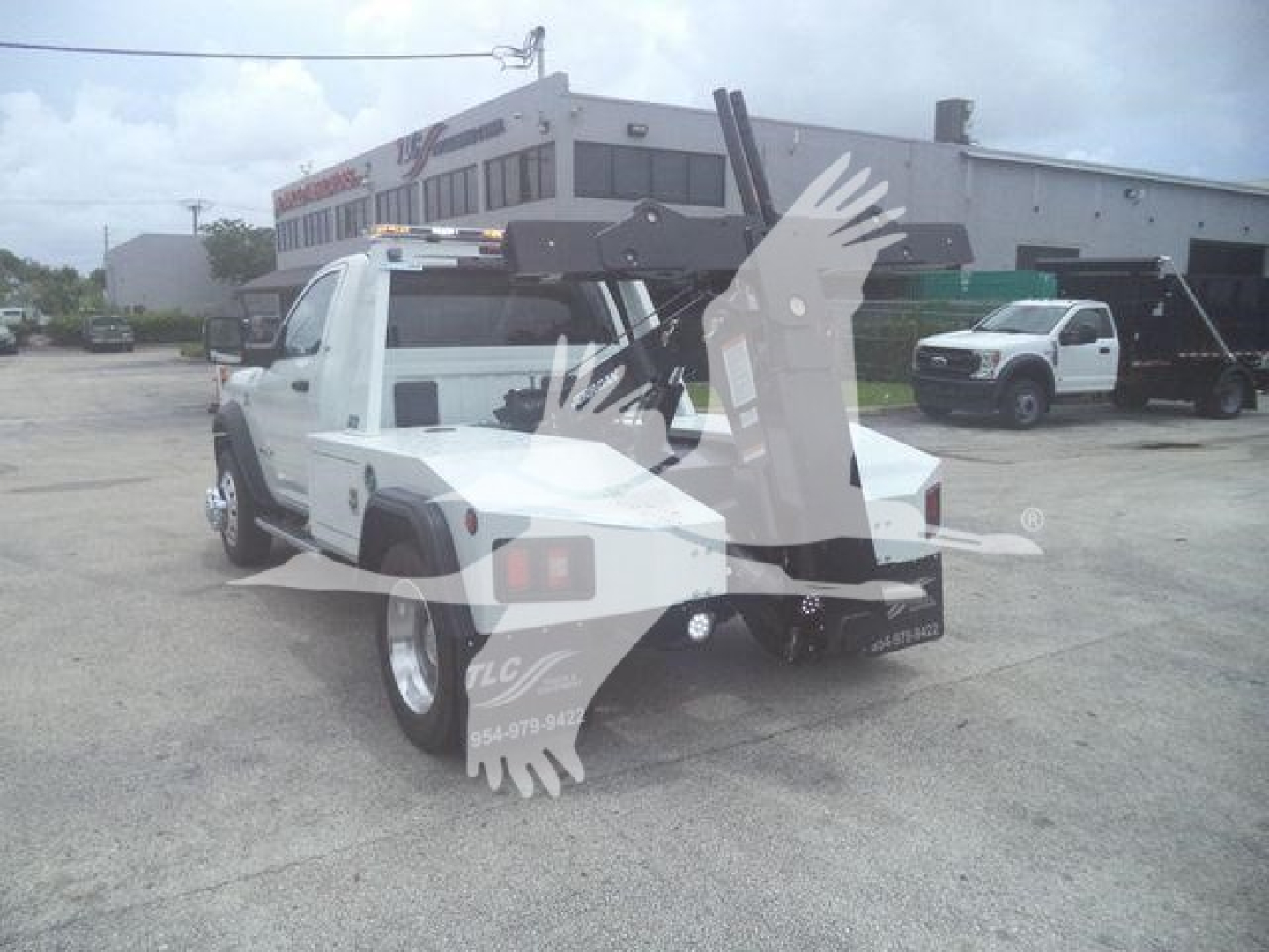 Ram 4500 tow truck with winch system mounted behind cab, white body, light bar on roof, rear hitch and towing apparatus visible.