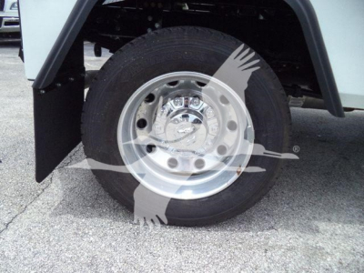 Truck wheel close-up showing aluminum wheel with hubcap and tire, fender flare and part of wheel well; watermark overlay present.