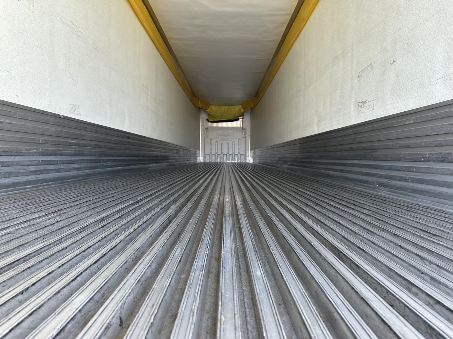 Trailer interior showing corrugated aluminum floor and side walls of a 2022 Utility 3000R reefer trailer, empty cargo area.
