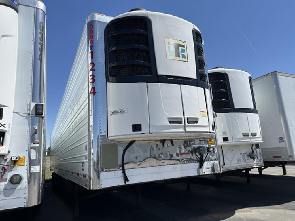 Utility 3000R trailer refrigeration unit mounted on front with white body and black grille, other trailers visible in a row.
