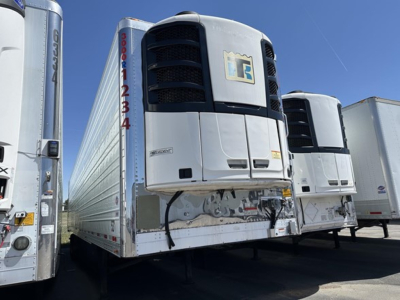 Utility 3000R trailer refrigeration unit mounted on front with white body and black grille, other trailers visible in a row.
