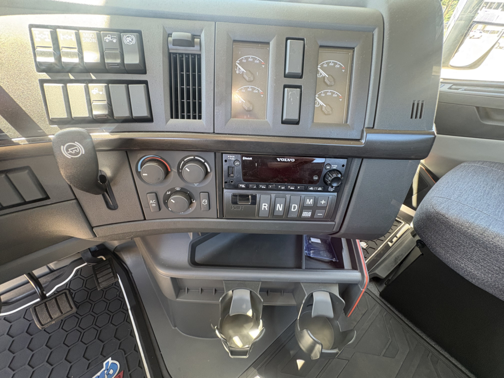 Volvo VHD64FT300 cab interior showing dashboard with gauges, climate controls, radio, and cup holders.