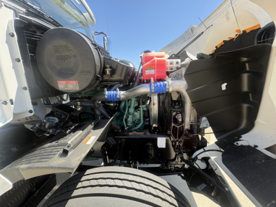 Engine bay of a Volvo VHD64FT300 cabover truck showing blue silicone hoses, air intake system, red coolant cap, and diesel engine block.