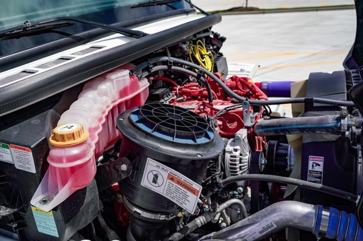 Freightliner Business Class M2 106 engine bay showing coolant reservoir, air intake, hoses, and electrical wiring.