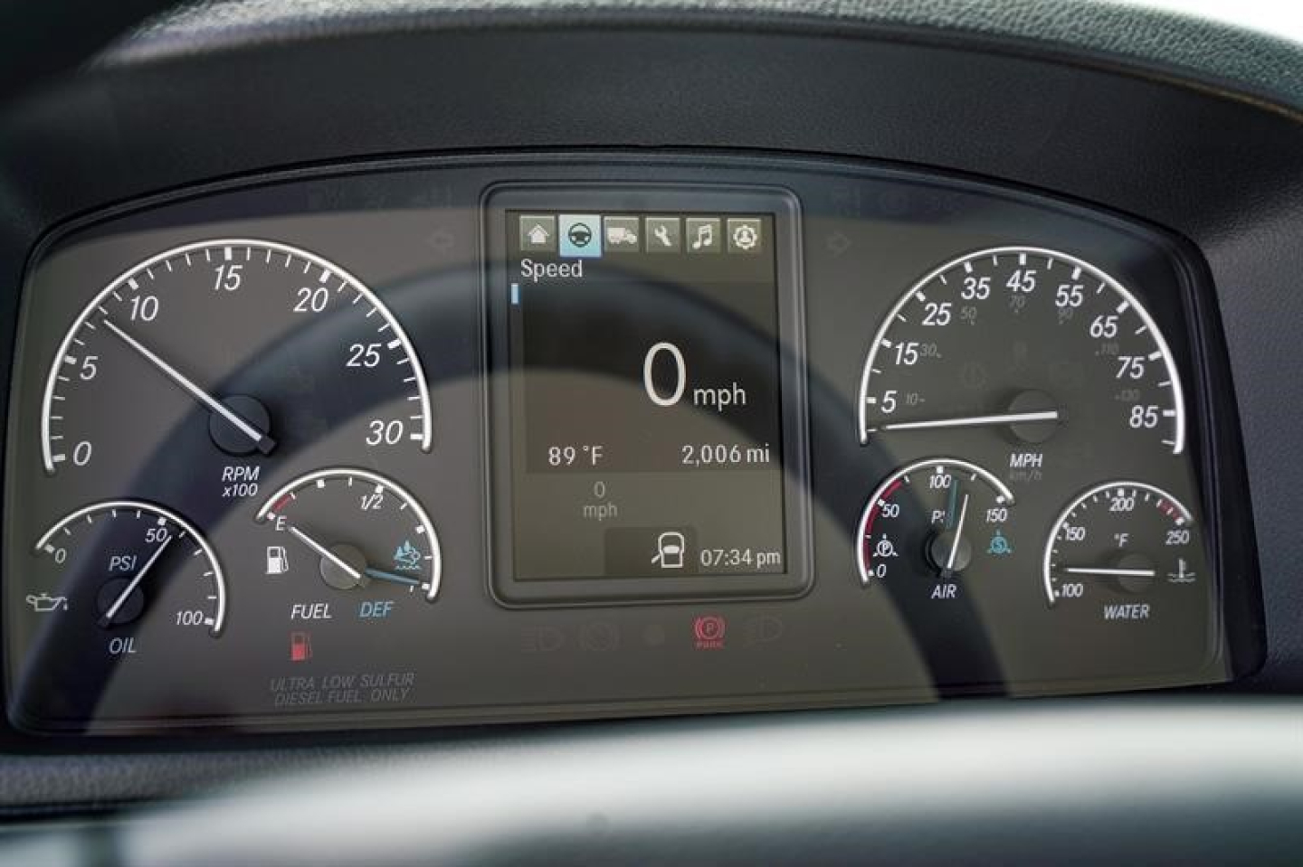 Dashboard of Freightliner Business Class M2 106 Plus showing digital display with 0 mph and various gauges; center screen shows 89°F, 2006 miles, time 07:34 pm; left tachometers, right speedometer and gauges.