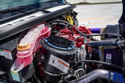 Freightliner Business Class M2 106 engine bay showing coolant reservoir, air intake, hoses, and electrical wiring.