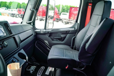Cab interior of a 2027 Freightliner Business Class M2 106 Plus with dark seats, panel, and window view showing the driver and passenger seats.