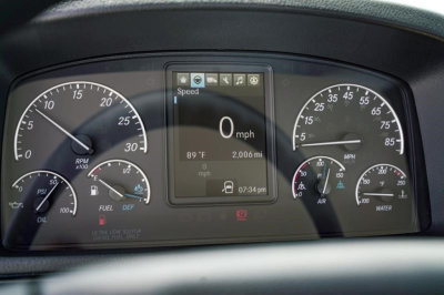 Dashboard of Freightliner Business Class M2 106 Plus showing digital display with 0 mph and various gauges; center screen shows 89°F, 2006 miles, time 07:34 pm; left tachometers, right speedometer and gauges.