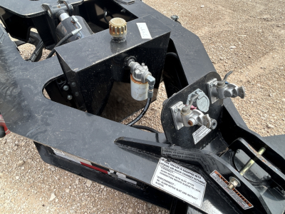 Load King trailer hitch assembly showing hydraulic and control components, caps, and warning labels on black steel frame.