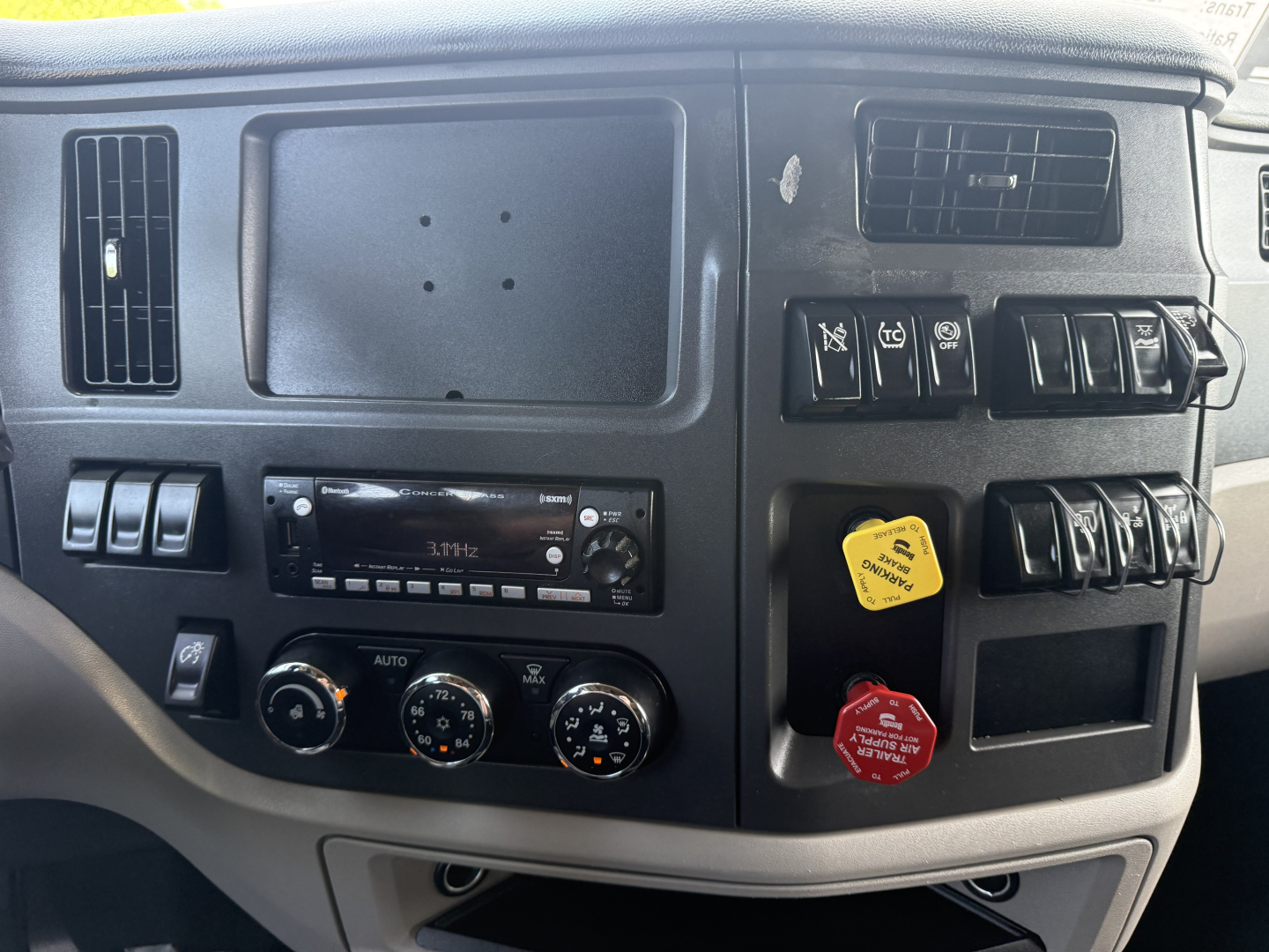 Peterbilt 579 truck cab interior dashboard controls and vents with radio, climate knobs, switches, and warning caps visible.