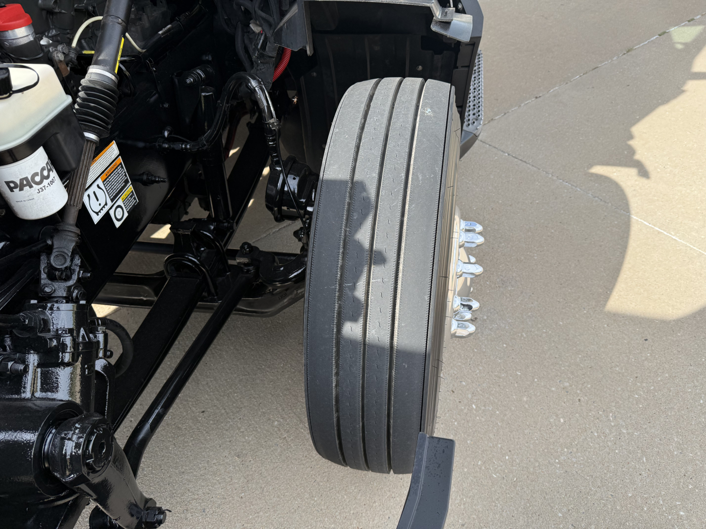 Truck wheel and front suspension area of a Peterbilt 579, showing a single wide dual-tire arrangement and exposed chassis components.