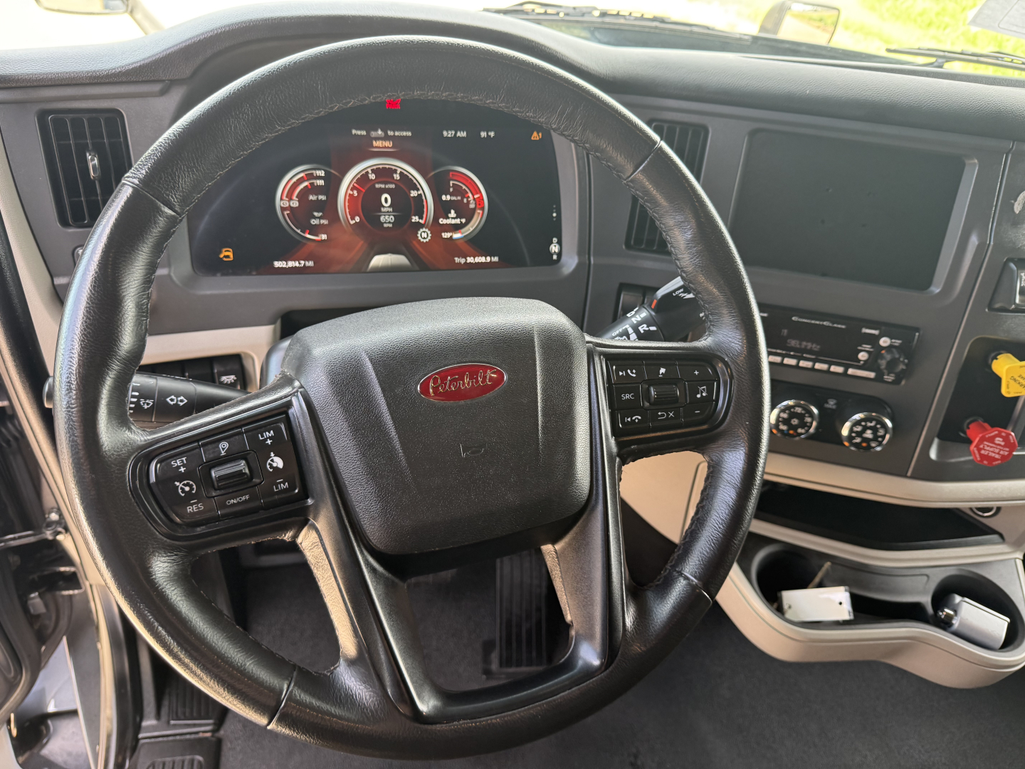 Peterbilt 579 interior cockpit with steering wheel, digital dashboard, and control panel showing gauges and buttons.