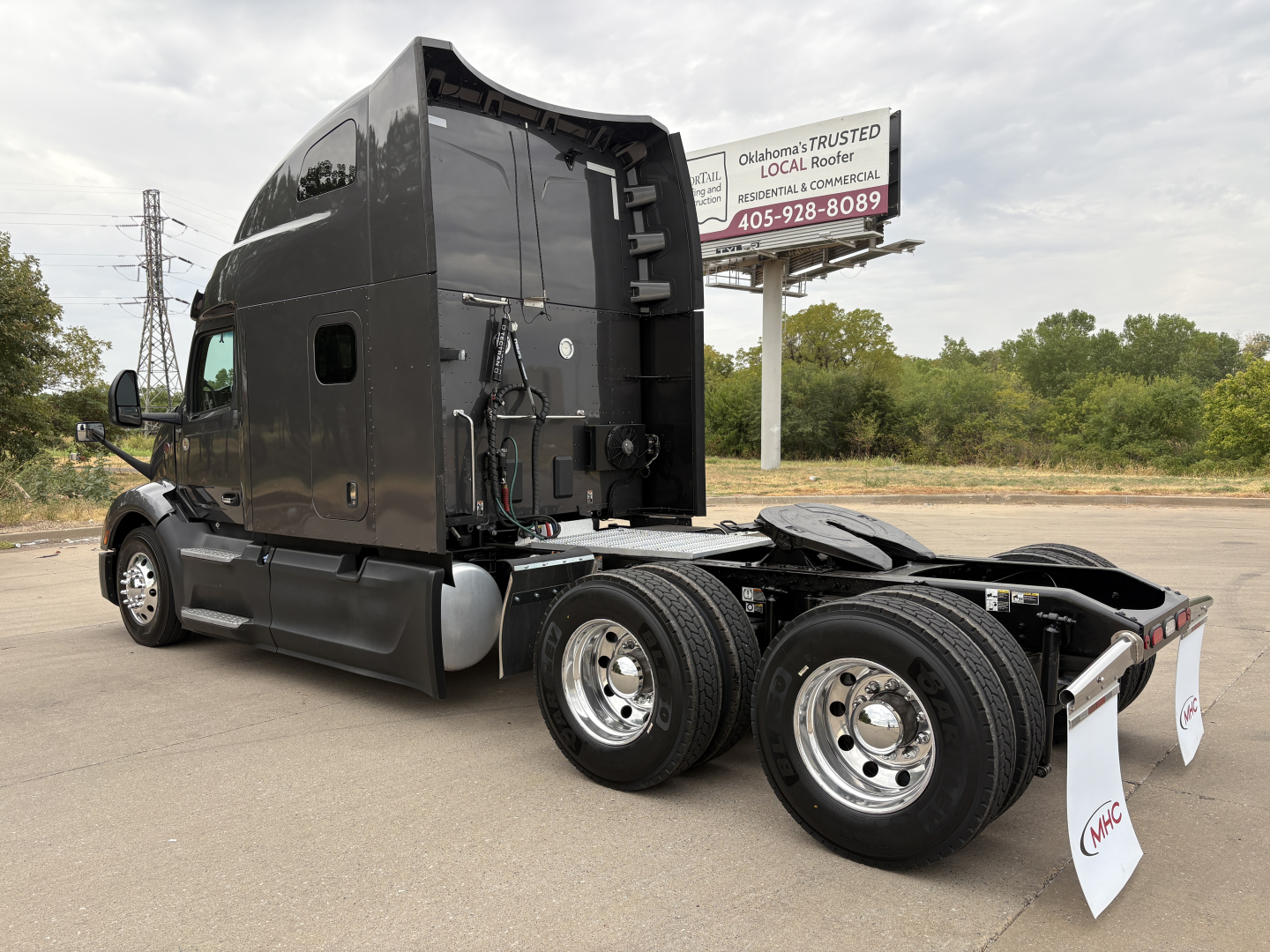 Peterbilt 579 tractor cab side and rear view showing dual rear axles and fifth wheel with black exterior and chrome wheels.