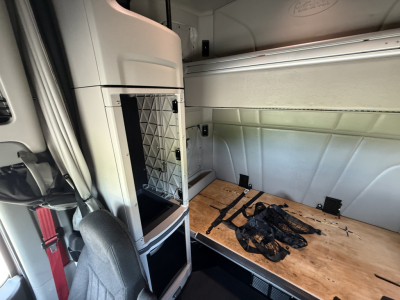Peterbilt 579 cabin area showing sleeper cab interior with side storage and wooden platform, cab frame and mounting hardware visible.