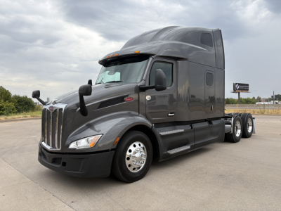Peterbilt 579 tractor in inventory, black/gray, cab with aerodynamic sleeper, front grille with Peterbilt emblem, dual rear axles, visible VIN plate area and stock number in listing.