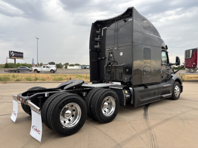 Peterbilt 579 sleeper tractor rear/side view showing chassis, dual rear axles, fifth wheel, and grey cab with exposed wiring and bumper markings.
