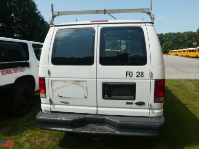 Ford E-Series van rear view showing dual doors, window, roof ladder rack, Ford emblem, and dealer plates.