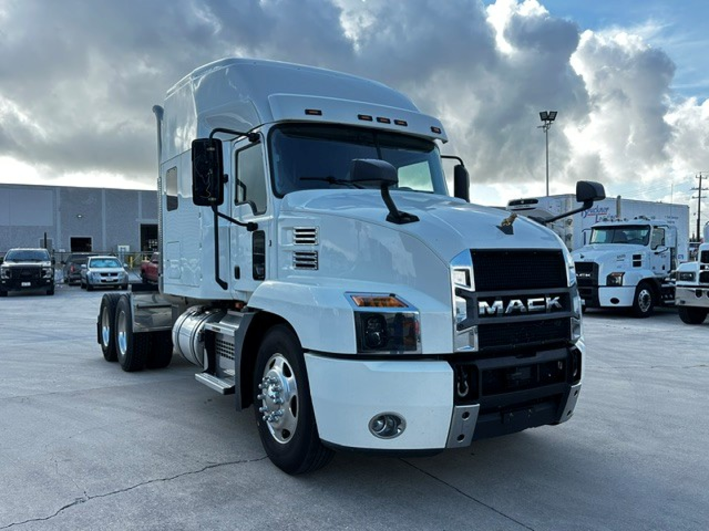 Truck image showing a white 2020 Mack AN64T70 conventional sleeper tractor with grille, cab mirrors, and dual rear axles parked in a lot.