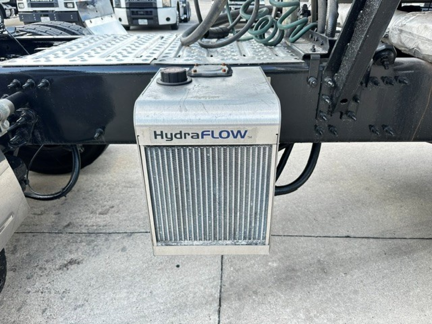 HydraFLOW auxiliary radiator/heat exchanger mounted under chassis with hoses and metal frame of Mack AN64T70 truck.
