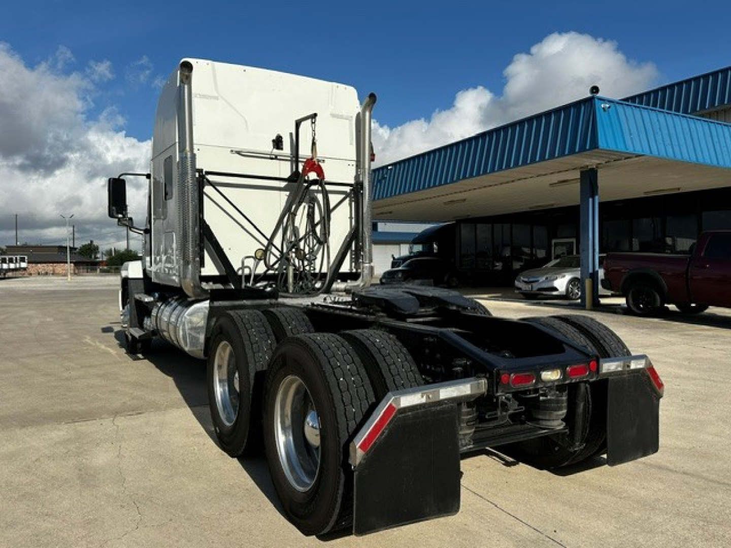 Mack AN64T70 semi-truck chassis and cab rear view showing dual rear axles and fifth wheel, with mud flaps and fuel tanks.