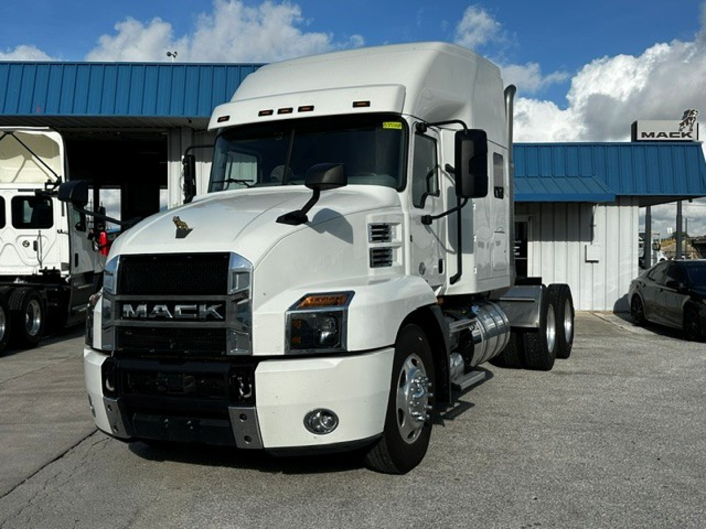 White Mack AN64T70 heavy-duty truck tractor in a dealership lot, front three-quarter view, with chrome grille and sleeper cab.
