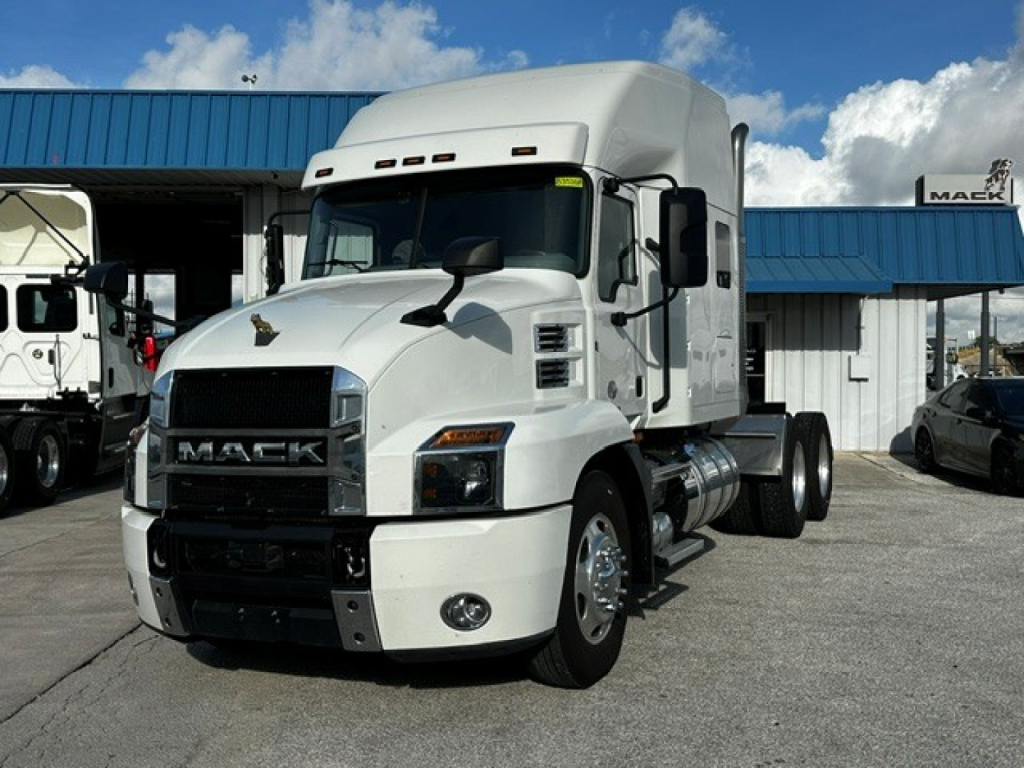 White Mack AN64T70 heavy-duty truck tractor in a dealership lot, front three-quarter view, with chrome grille and sleeper cab.