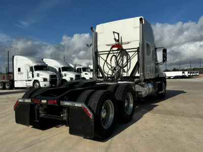 Truck chassis with sleeper cab rear view showing dual rear axles and fifth-wheel area, Mack AN64T70 tag in yard.