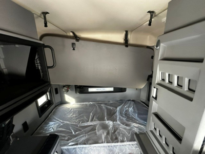 Truck cab interior showing sleeping area with plastic-covered mattress and overhead storage compartments, Mack AN64T70 interior detail