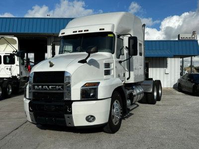 White Mack AN64T70 heavy-duty truck tractor in a dealership lot, front three-quarter view, with chrome grille and sleeper cab.