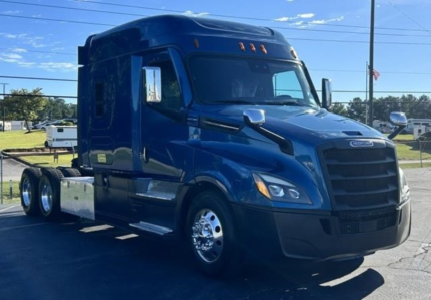 Freightliner Cascadia tractor in blue, side view showing sleeper cab and dual rear axles with chrome wheels.