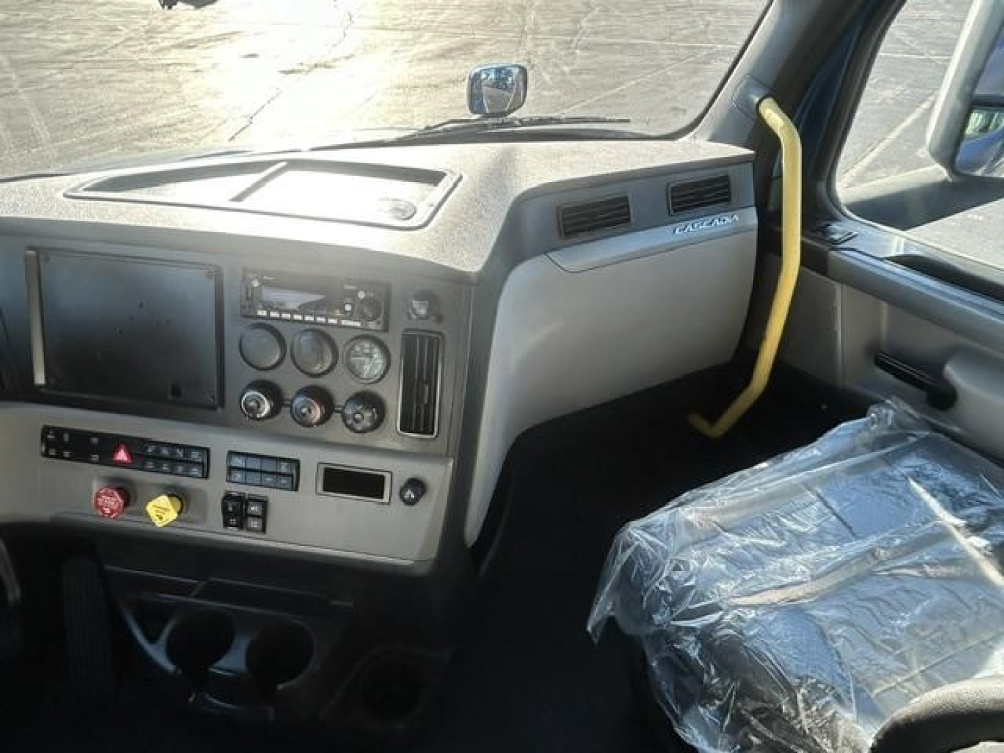 Freightliner Cascadia driver area showing dashboard and steering wheel with yellow rail near windshield