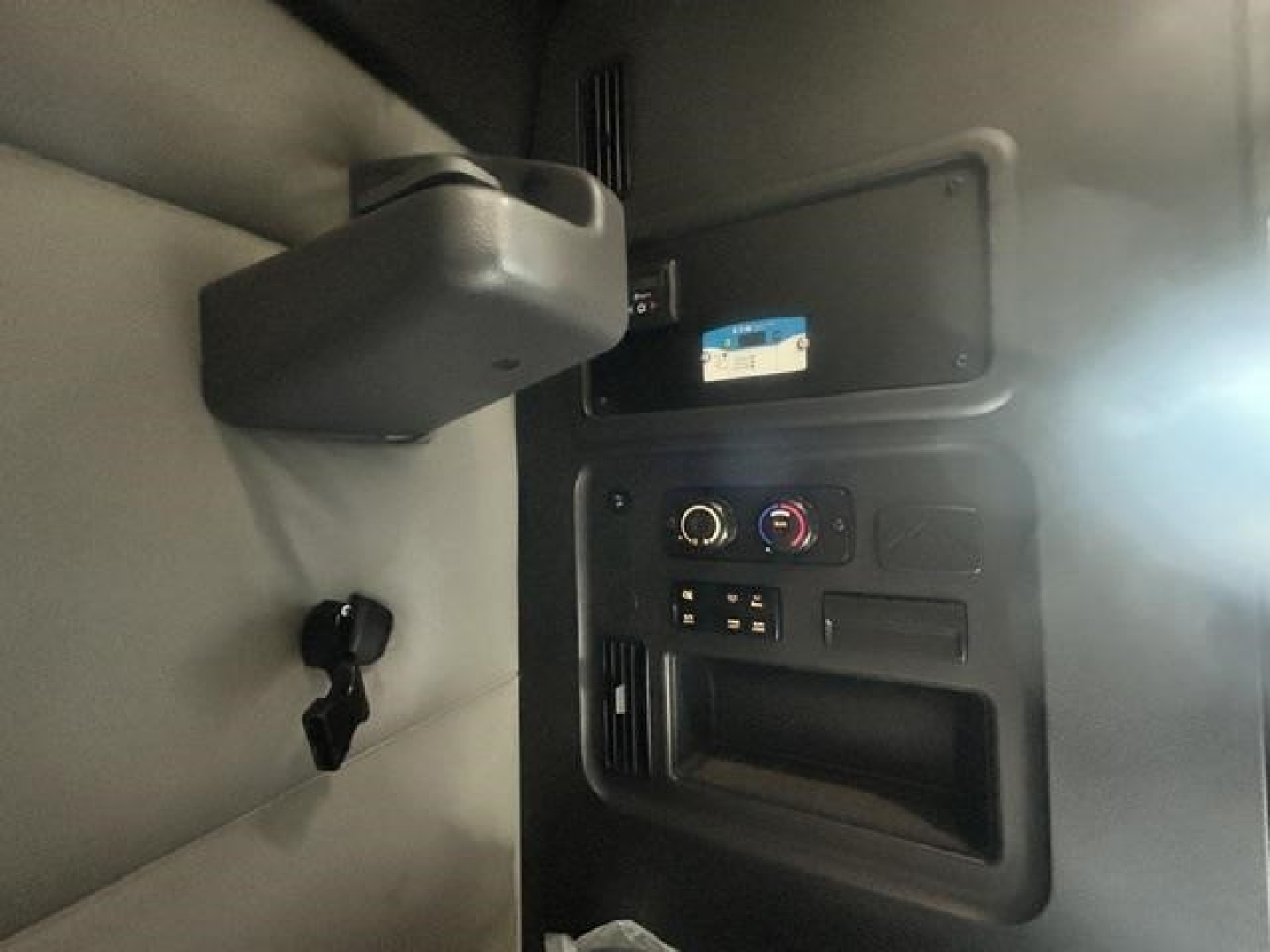 Interior view of a Freightliner Cascadia cab dashboard with controls and a small screen. Visible text on a label and a control panel.