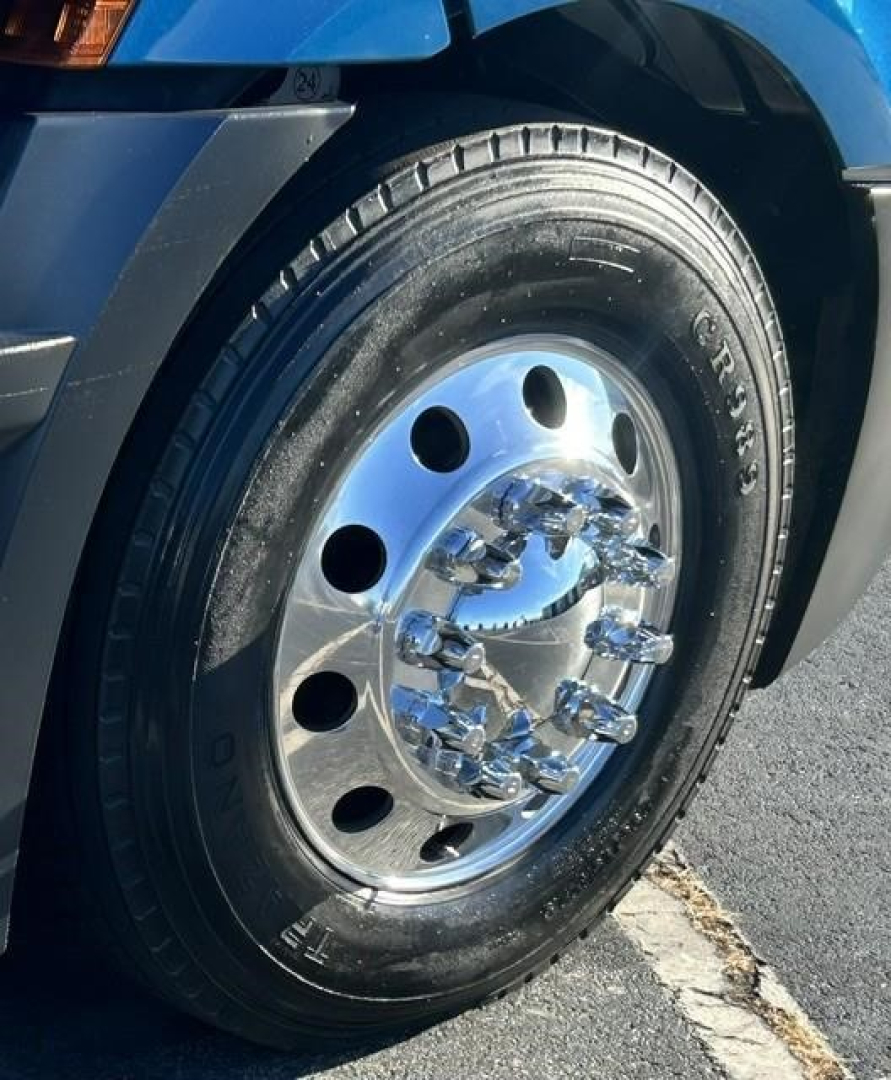 Wheel of a Freightliner Cascadia truck showing polished chrome hub with multiple lug nuts and tire treads.