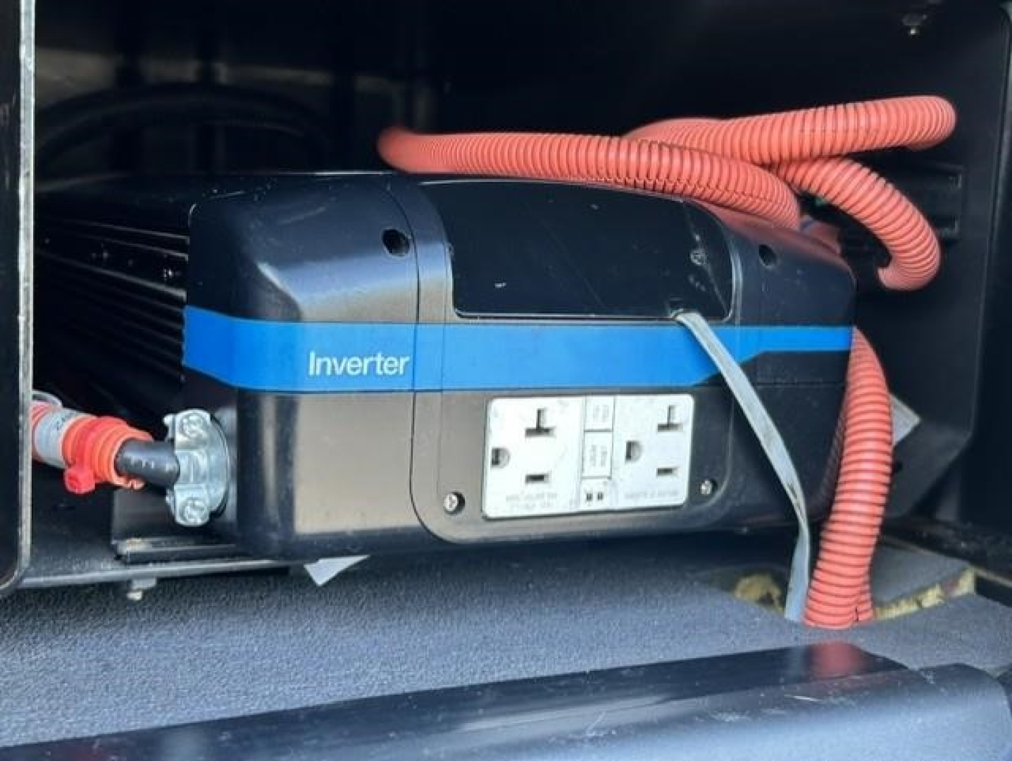 Inverter mounted in Freightliner Cascadia engine area with red cables and dual 120V outlets.