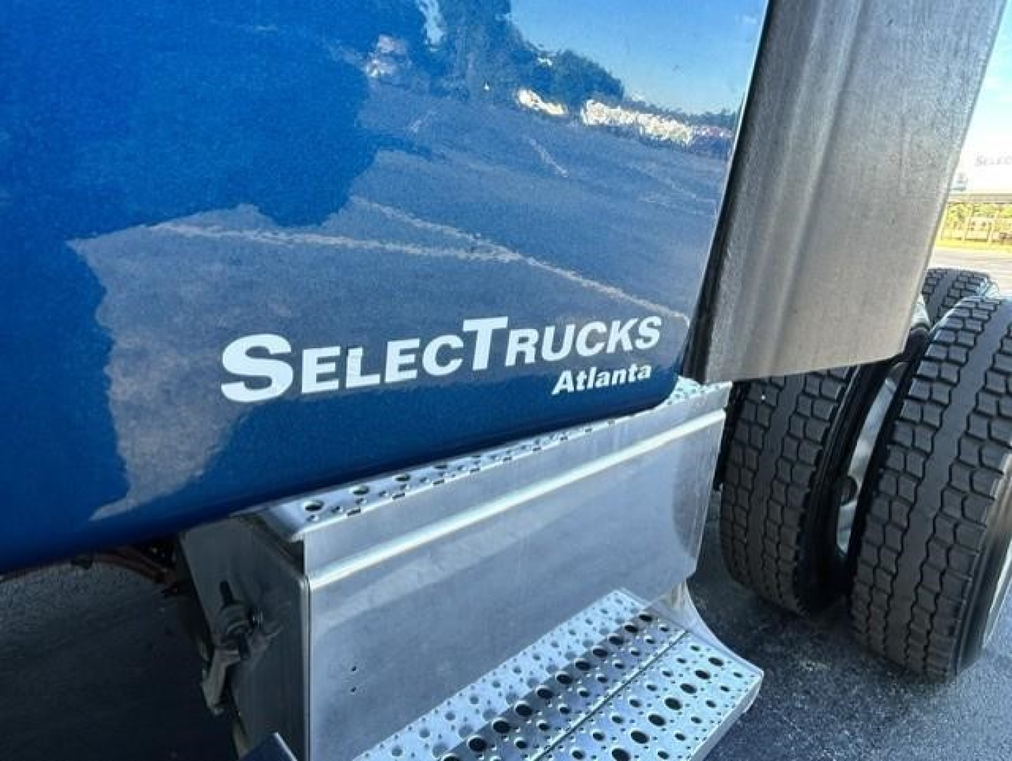 Truck side panel shows 'SELECTTRUCKS Atlanta' logo on blue cab with metal step and dual rear wheels.