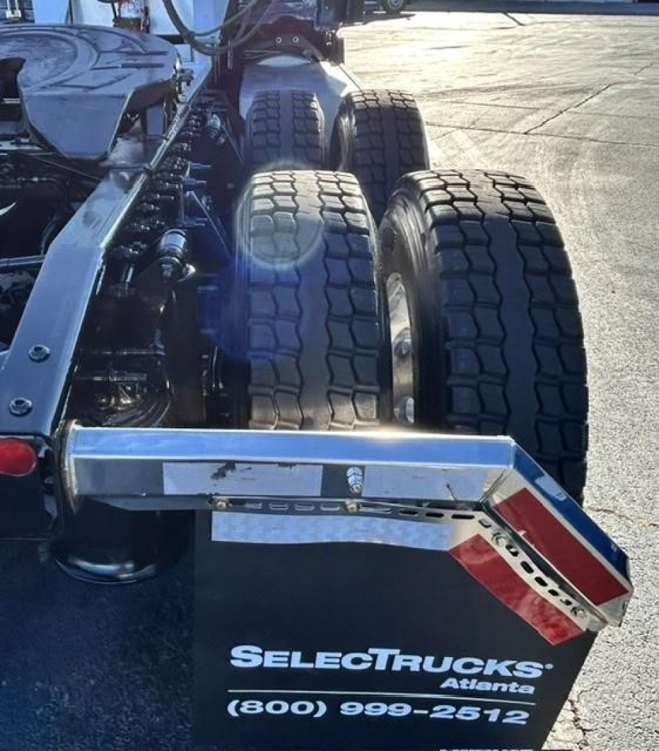 Truck rear view showing dual rear axles and SelectTrucks Atlante chrome bumper with reflective red/white stripes and bumper plate.
