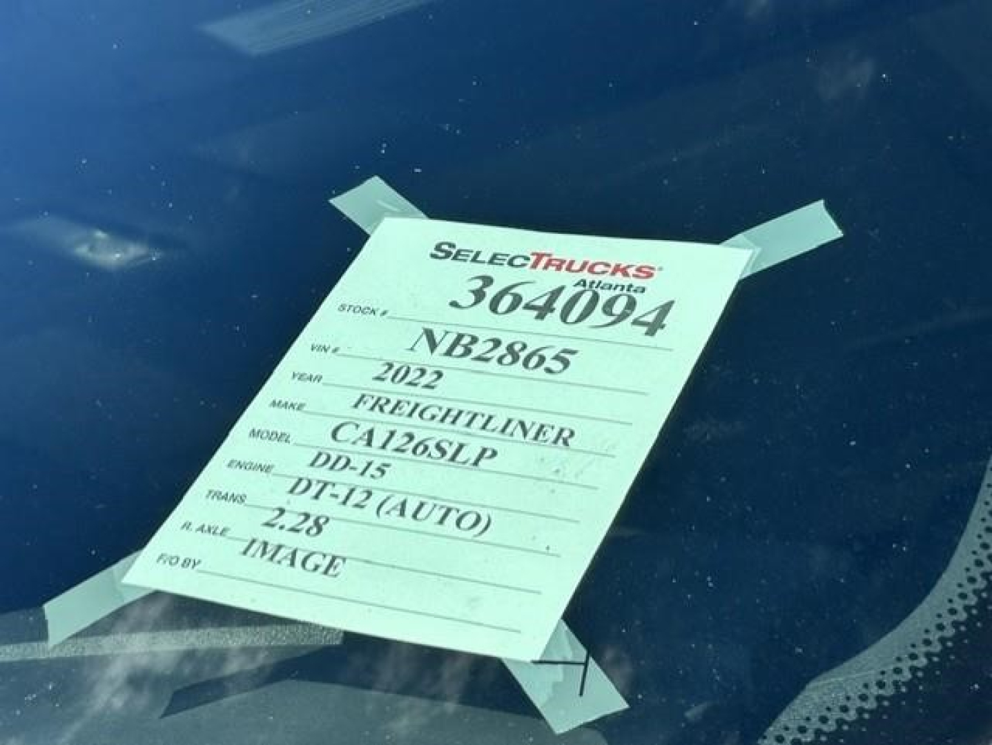 Tag on windshield showing stock number 364094, VIN NB2865, year 2022 Freightliner, model CA126SLP, DD-15 engine, auto transmission, 2.28 axle, image label.