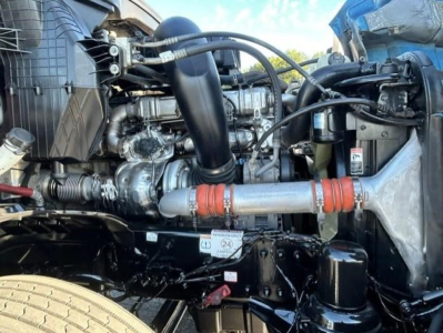 Engine bay of a 2022 Freightliner Cascadia showing intake tubing, hoses, and exhaust components.
