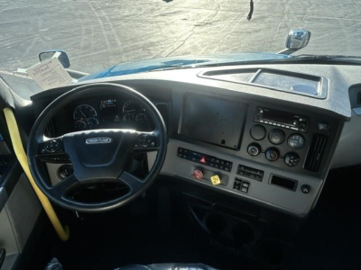 Cab interior of 2022 Freightliner Cascadia with steering wheel, instrument cluster, dash gauges, and center console; visible screens and controls.