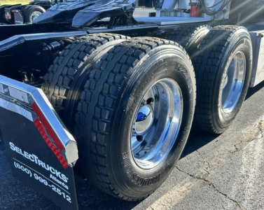 Freightliner Cascadia rear dual rear axles with dual tires and chrome rims; trailer/loader area showing wheel well and a black chassis. Side of equipment has text: SELECT TRUCKS and phone number (800) 699-2612 on a dark plate.
