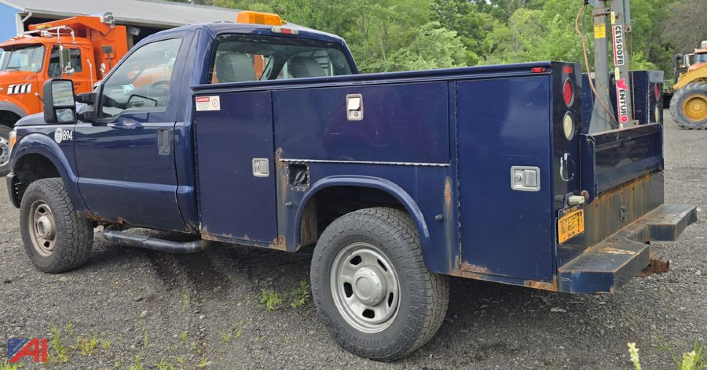 Ford F-350 Super Duty utility service truck with plow and utility box, blue cab and cargo bed, side view showing storage compartments and rear bumper, used condition.